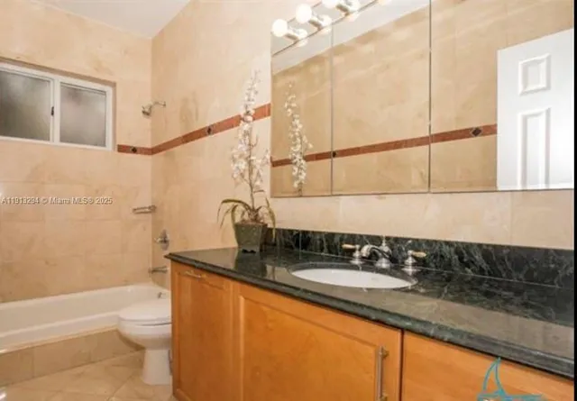 a bathroom with a granite countertop sink a toilet and shower