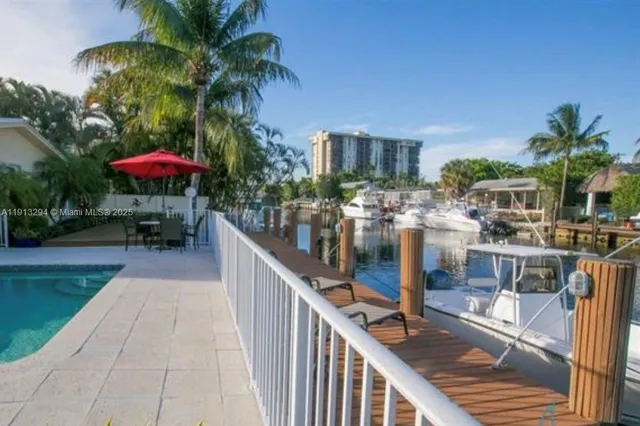 a view of a patio with a table and chairs under an umbrella with palm trees
