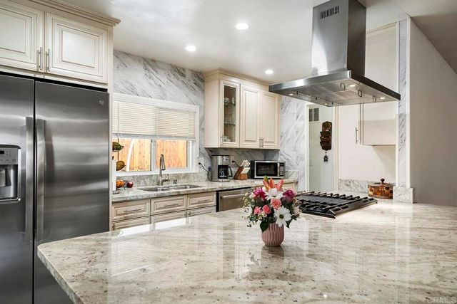 a kitchen with stainless steel appliances granite countertop a sink stove and refrigerator