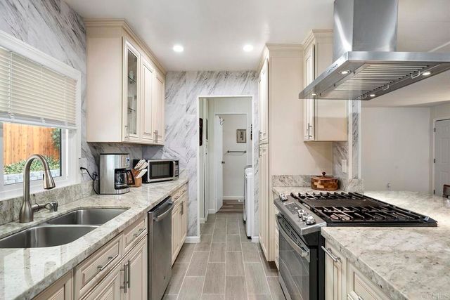 a kitchen with stainless steel appliances granite countertop a sink a stove and a refrigerator