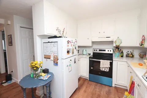 a kitchen with stainless steel appliances a stove a refrigerator white cabinets and wooden floor