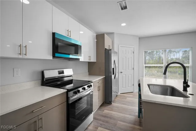a kitchen with stainless steel appliances a stove a sink and a microwave