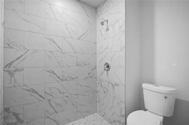 a white toilet sitting next to a shower