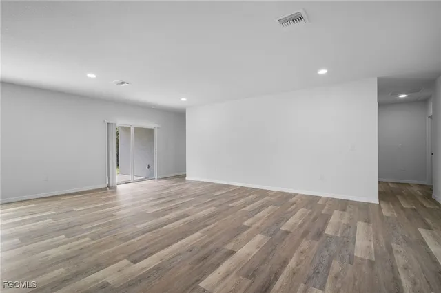 an empty room with wooden floor and natural light