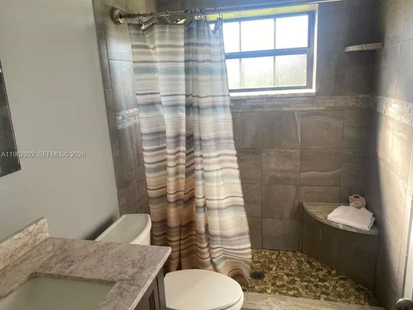 a bathroom with a granite countertop toilet a sink and a shower