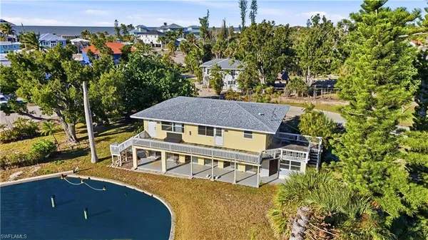an aerial view of a house with swimming pool and large trees