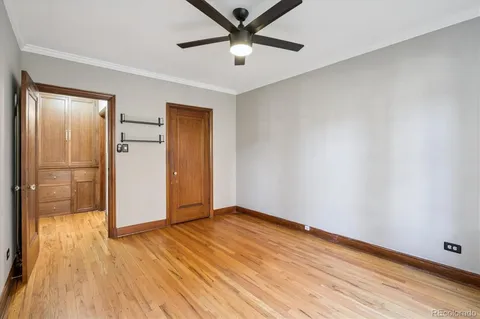 a view of empty room with wooden floor and fan
