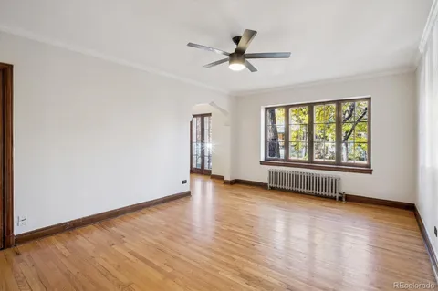 a view of empty room with wooden floor and fan