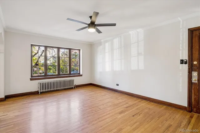 an empty room with wooden floor fan and windows