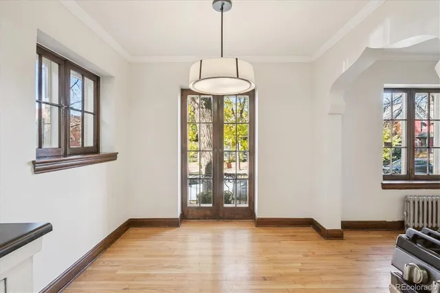 a view of an empty room with window and hardwood floor