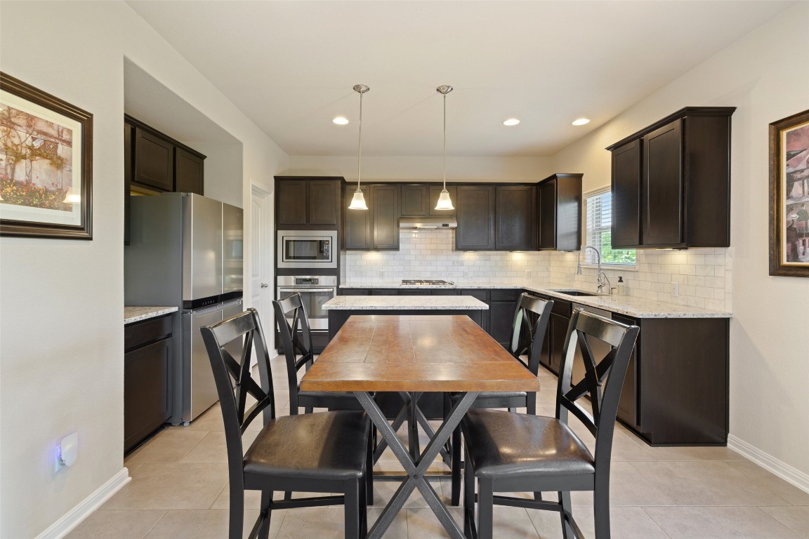 609 Stone View Trail Austin, TX 78737 - Photo 12 of 36 a kitchen with a dining table chairs and refrigerator