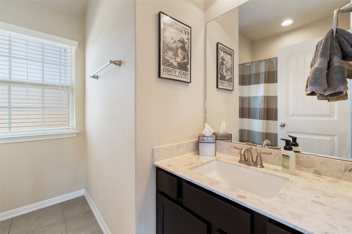 609 Stone View Trail Austin, TX 78737 - Photo 23 of 36 a bathroom with a granite countertop sink a mirror a vanity and a shower