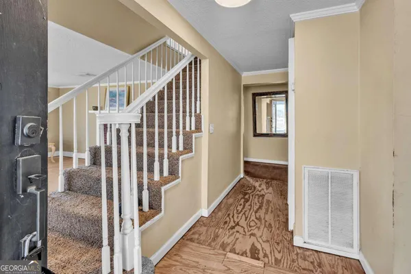 a view of a hallway with wooden floor and staircase