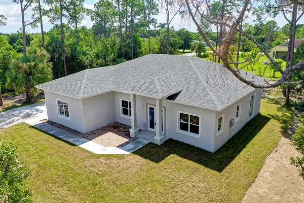 a aerial view of a house next to a yard with big trees
