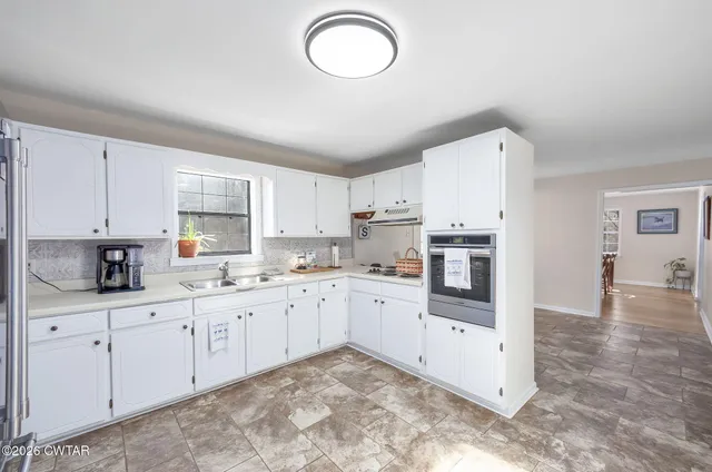 a kitchen with granite countertop a refrigerator stove and white cabinets