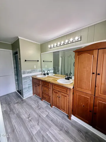 a spacious bathroom with a double vanity sink a large mirror and a shower