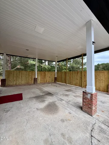 a view of empty room with wooden floor and kitchen