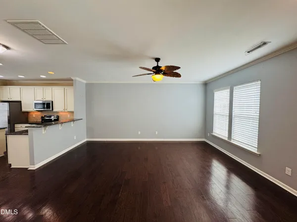 a view of an empty room with kitchen stove and wooden floor
