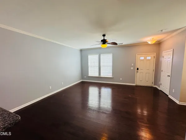 a view of an empty room with wooden floor and a window