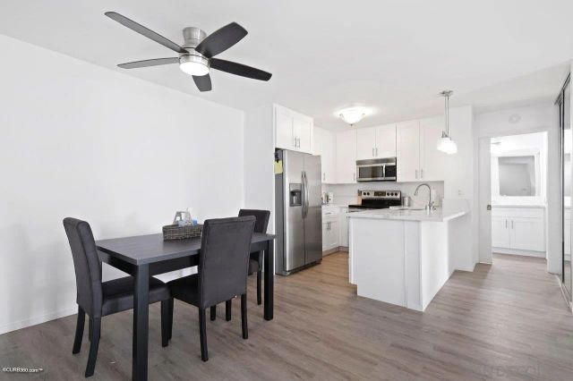 a kitchen with stainless steel appliances kitchen island granite countertop a dining table chairs and a refrigerator