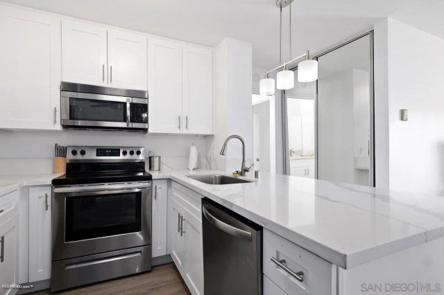 a kitchen with granite countertop a sink cabinets and stainless steel appliances