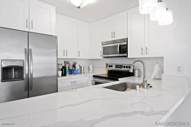 a kitchen with a refrigerator a microwave a sink and cabinets