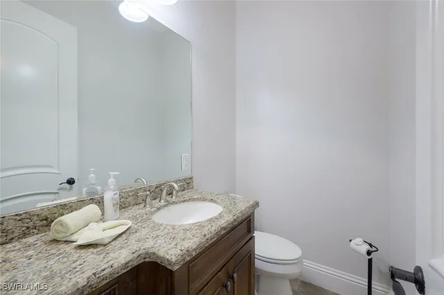 a bathroom with a granite countertop sink a toilet and a mirror