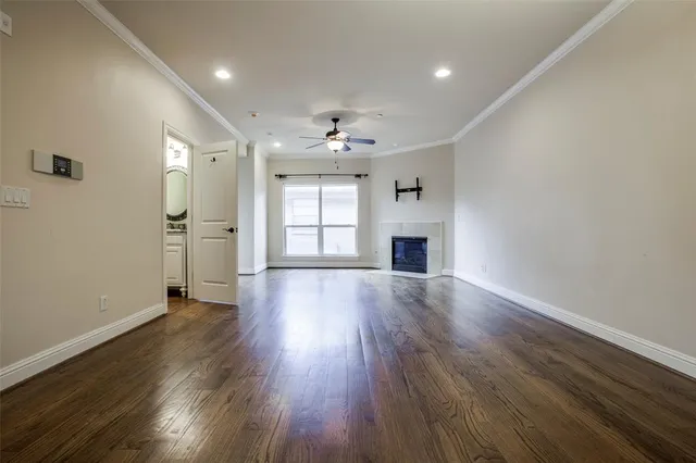 an empty room with wooden floor fireplace and windows