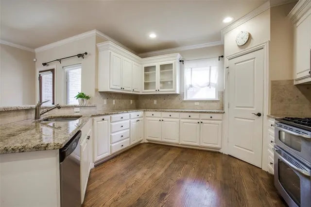 a kitchen with granite countertop a sink cabinets wooden floor and stainless steel appliances