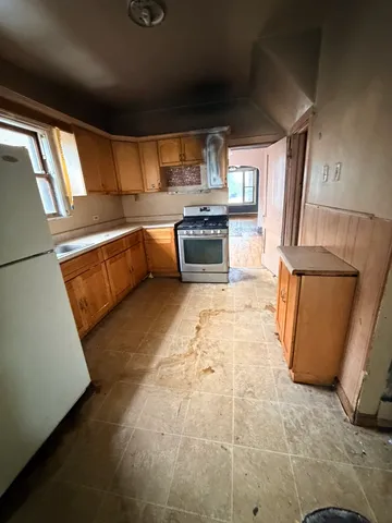 a kitchen with stainless steel appliances granite countertop a refrigerator a stove and a sink with wooden floor