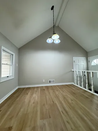 an empty room with wooden floor and chandelier