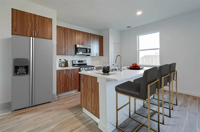 a kitchen with stainless steel appliances kitchen island granite countertop a sink refrigerator and cabinets