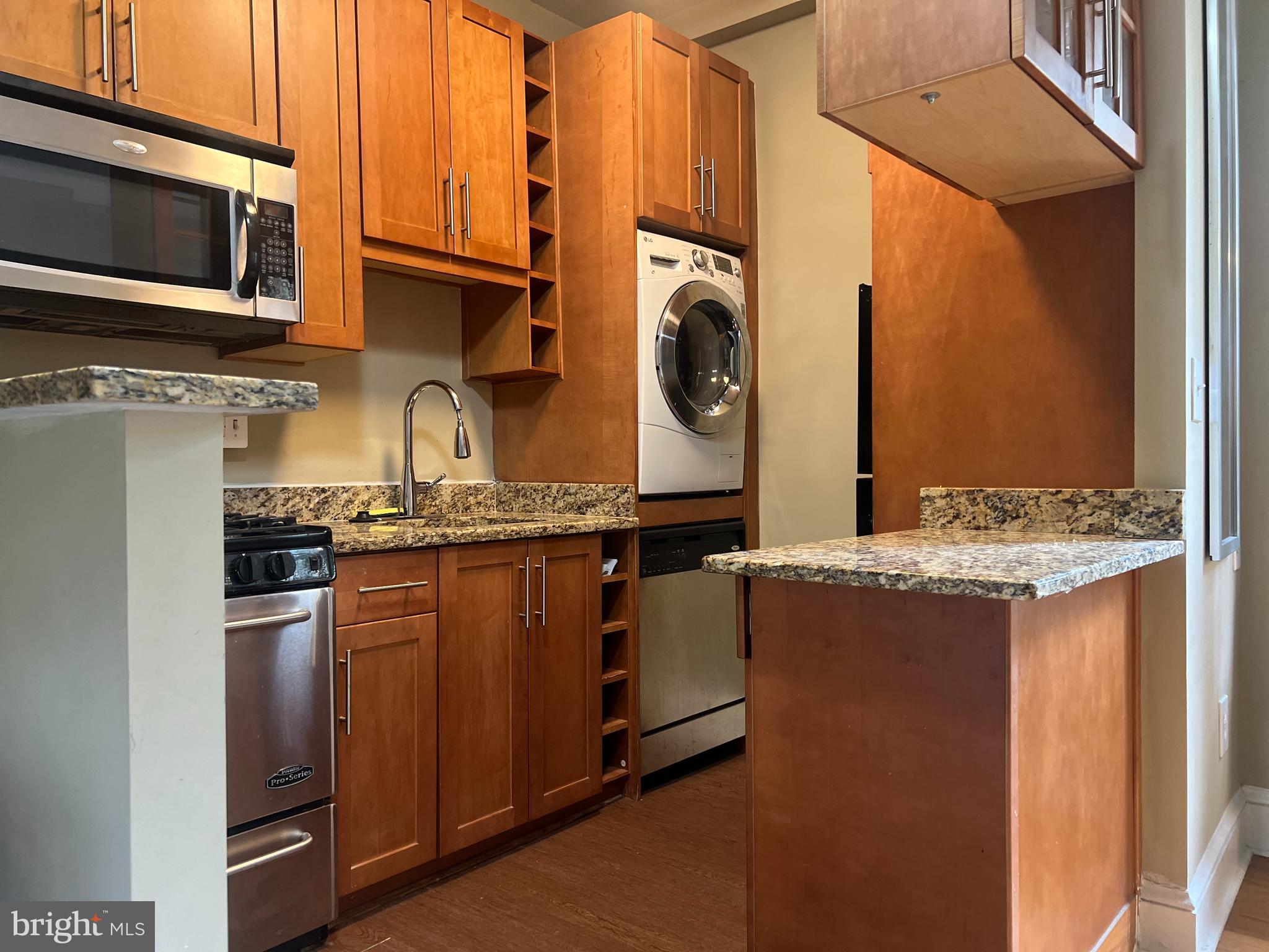 6645 Georgia Avenue Northwest, Unit 101 Washington, DC 20012 - Photo 5 of 7 a kitchen with stainless steel appliances granite countertop a stove a sink and a microwave