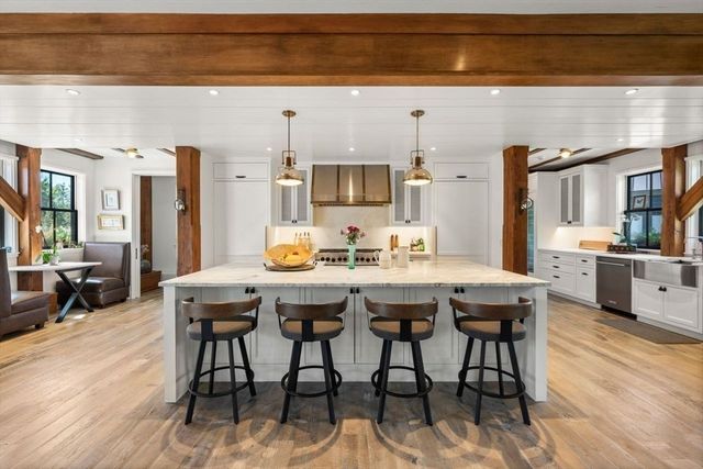 a dining hall with stainless steel appliances kitchen island granite countertop a dining table and chairs with wooden floor