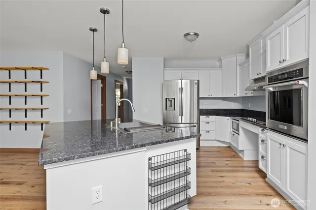a kitchen with stainless steel appliances granite countertop a sink and a refrigerator