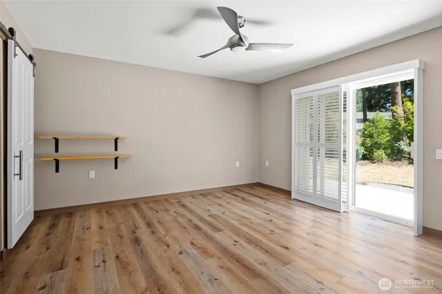 a view of empty room with wooden floor and fan