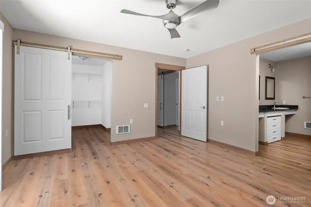 an empty room with wooden floor cabinet and windows