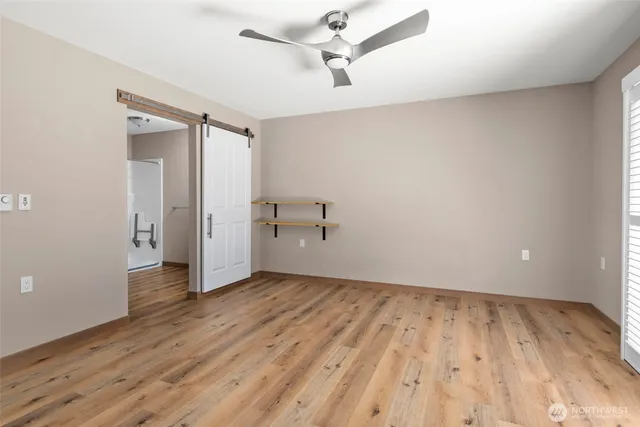 an empty room with wooden floor ceiling fan and windows