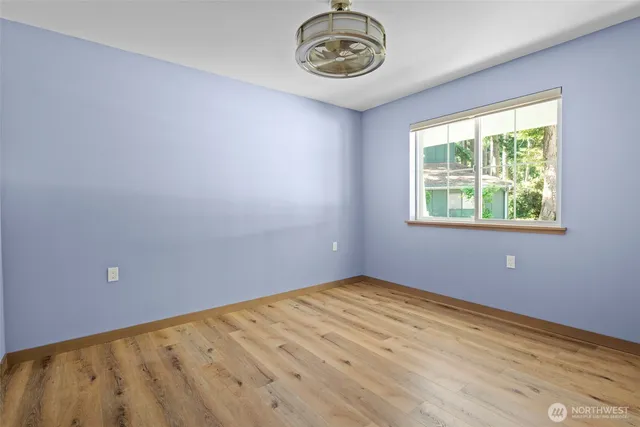 a view of empty room with wooden floor and window