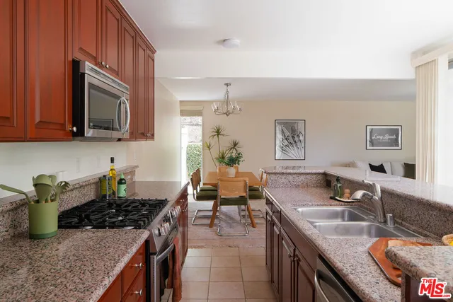 a kitchen with granite countertop a sink a stove and wooden cabinets