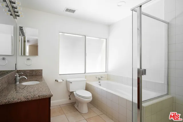 a bathroom with a granite countertop sink a toilet and bathtub