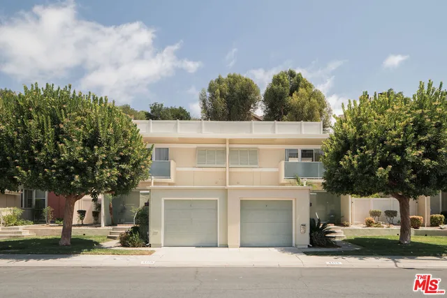 a view of a white building among the street and trees