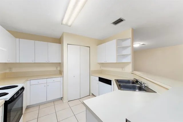 a kitchen with a sink a stove a refrigerator and white cabinets