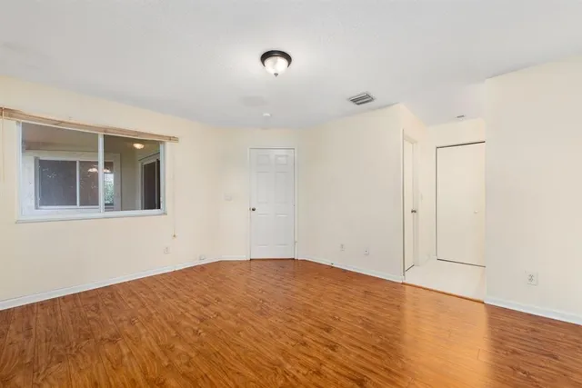 a view of empty room with wooden floor and fan