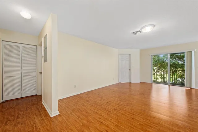 an empty room with wooden floor and windows
