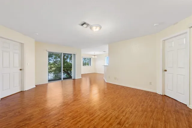 an empty room with wooden floor and windows