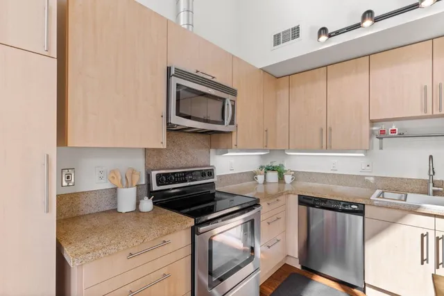 a kitchen with stainless steel appliances granite countertop a sink stove and microwave