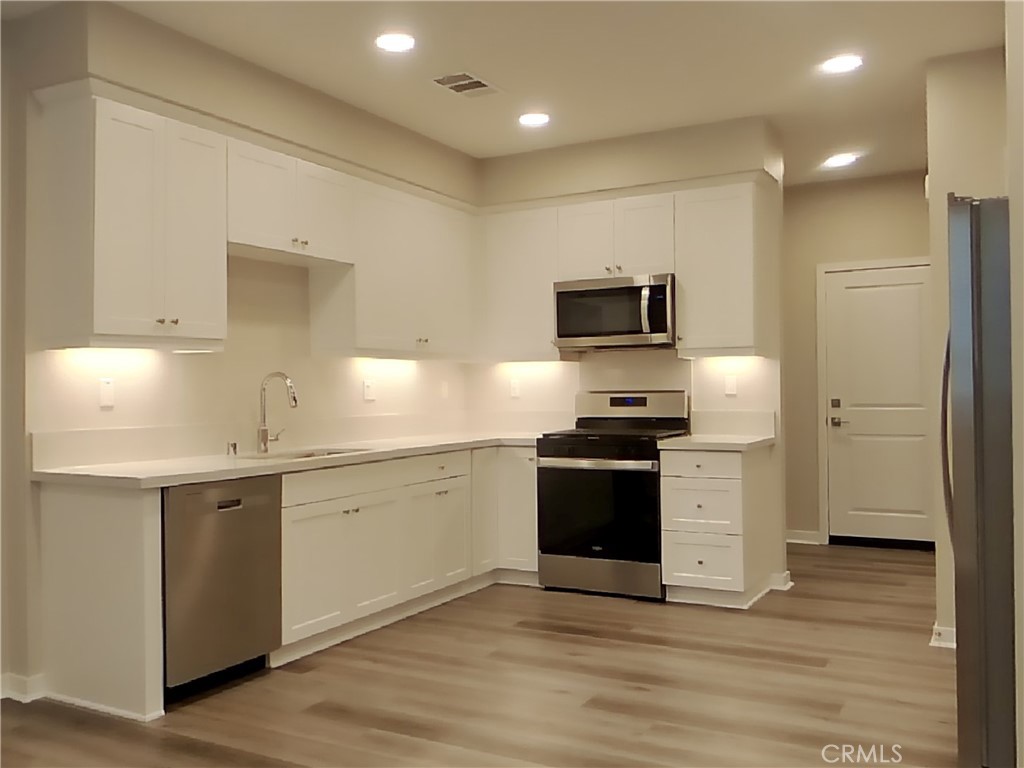 24944 Siempre Court Wildomar, CA 92595 - Photo 5 of 31 a kitchen with granite countertop a stove and a refrigerator