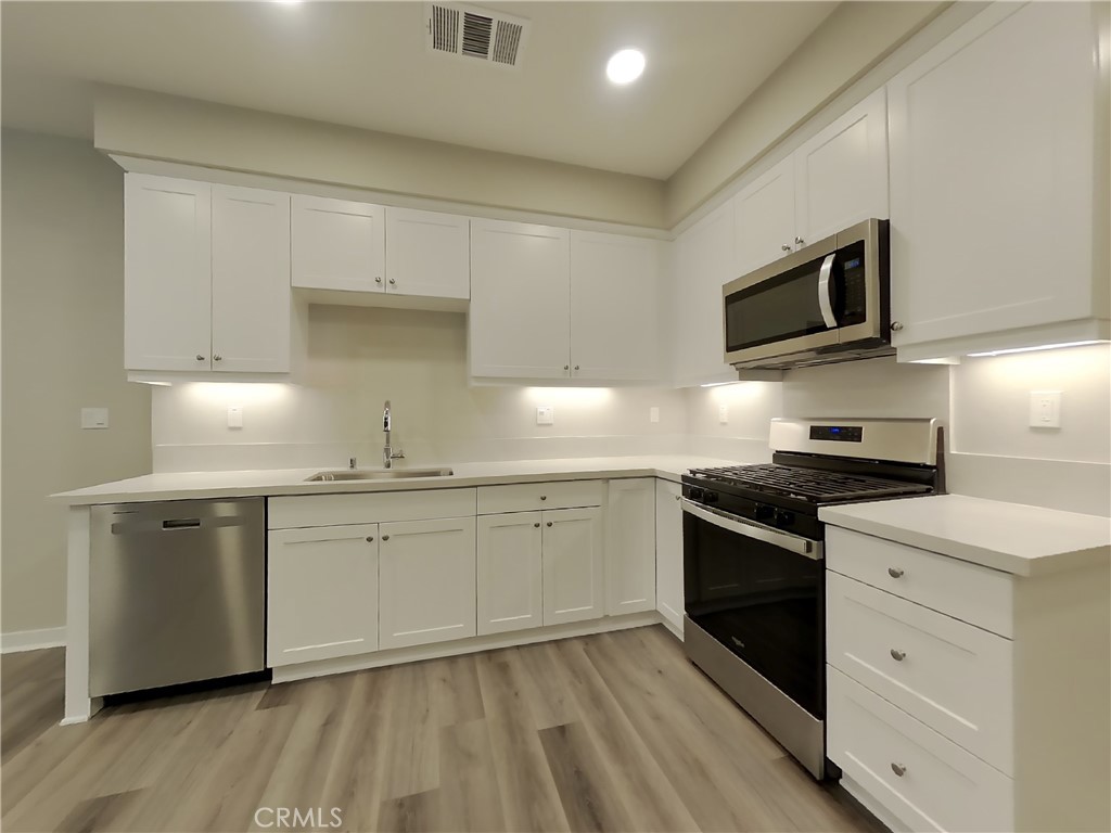 24944 Siempre Court Wildomar, CA 92595 - Photo 6 of 31 a kitchen with granite countertop cabinets stainless steel appliances and wooden floor