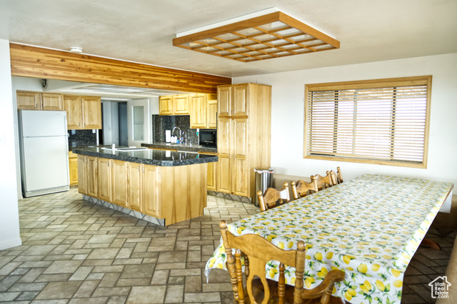 588 Raspberry Patch Road Garden City, UT 84028 - Photo 34 of 74 Kitchen with decorative backsplash, light brown cabinetry, freestanding refrigerator, a kitchen island, and brick flooring